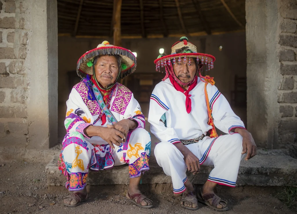 Dos personas de la raza huichol posando con trajes caracteristicos